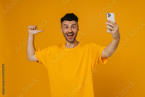Young white unshaven man laughing while using cellphone
