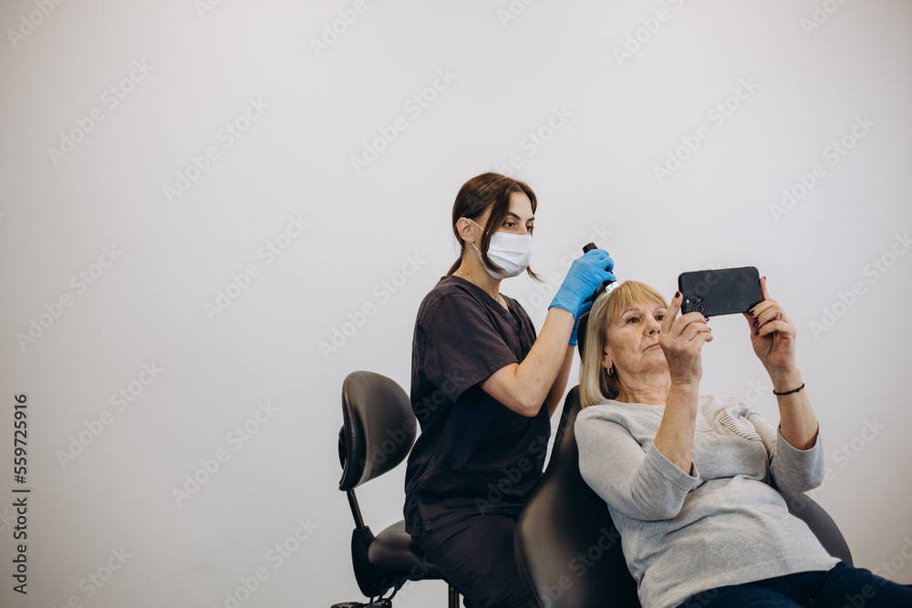 Εκτύπωση καμβά Doctor trichologist examines woman patient's hairs using trichoscope in clinic