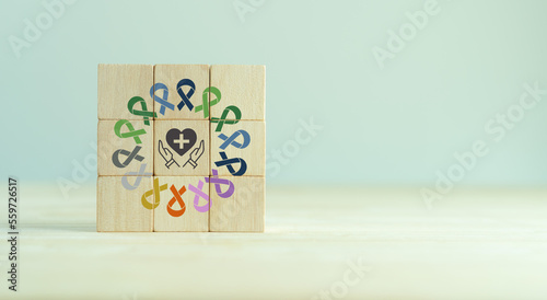 Cancer health insurance concept. Colorful ribbons with insurance icon on wooden cube blocks background. Health insurance for cancer care. Healthcare, medical and world cancer day (February 4) concept.