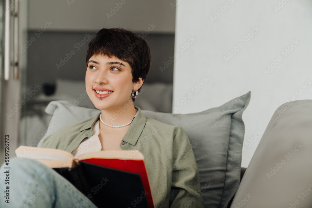 Smiling woman reading book while sitting on couch Smiling woman reading book while sitting on couch