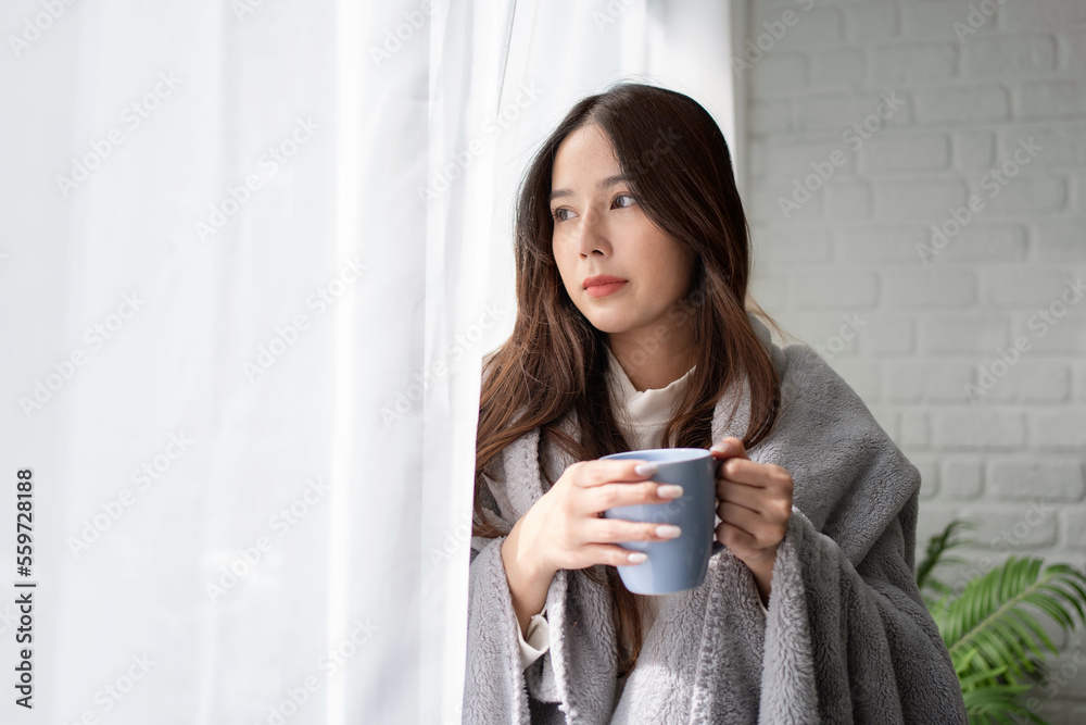 Portrait of Beautiful asian woman in casual clothes standing by large window She looking outside and drinking tea Portrait of Beautiful asian woman in casual clothes standing by large window She looking outside and drinking tea
