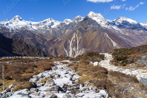 A high plateau with a frozen mountain river during the Kanchenjunga Base Camp Trek in Nepal. The trek offers stunning views of the third-highest mountain in the world and its surrounding peaks.