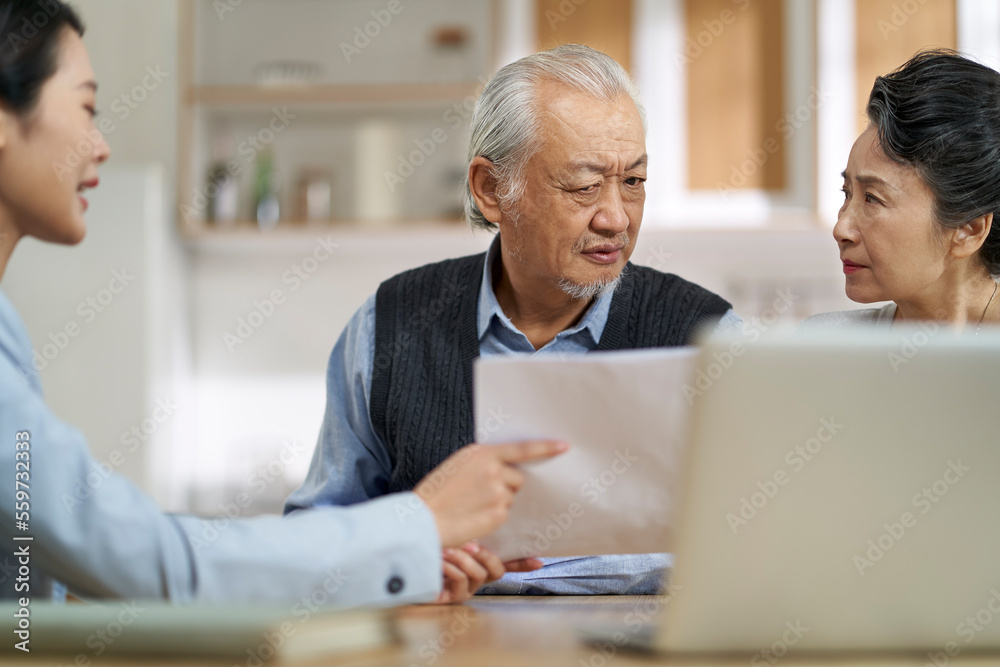 senior asian couple appears to be unconvinced and confused while listening to a saleswoman senior asian couple appears to be unconvinced and confused while listening to a saleswoman