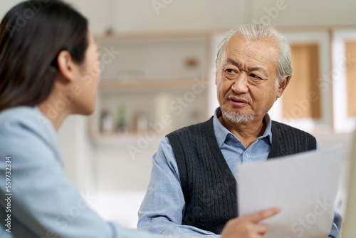 Fototapeta asian old man appears to be unconvinced while listening to a salesperson