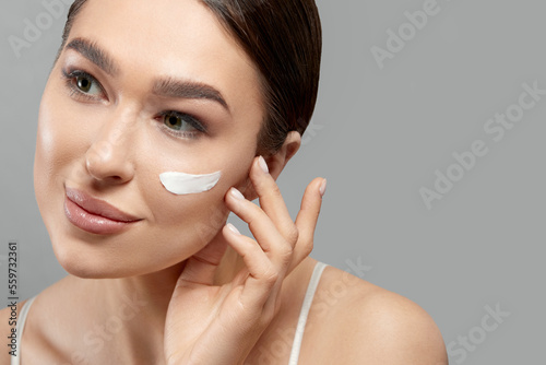 Closeup happy young woman applying cream to her face Skin care and cosmetics concept. Cosmetics. Beauty Woman face skin care.Natural makeup, touching face. photo