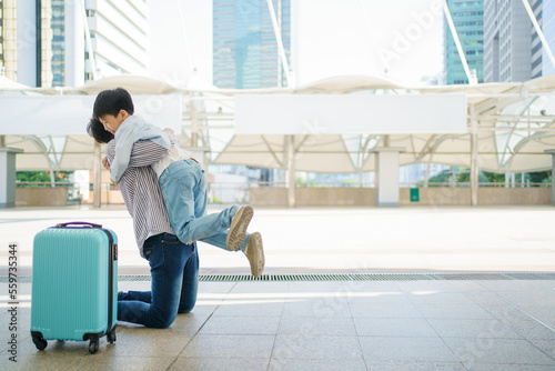 Happy cheerful Asian little boy running to his father at the railway or sky train station after his father returned from the traveling trip. Happy Asian family father and son concept.