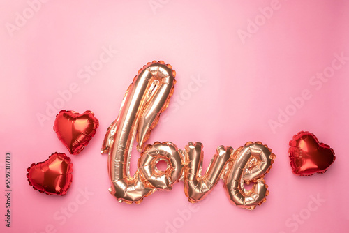 Pale pink Foil Balloons in the shape of the word Love with hearts on pink background.