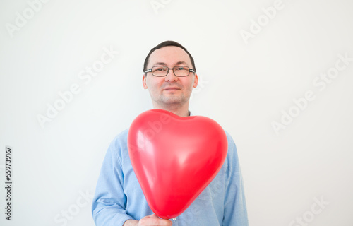 Young man in glasses hold Love balloon on white background. Valentines day,anniversary,birthday concept © piksik