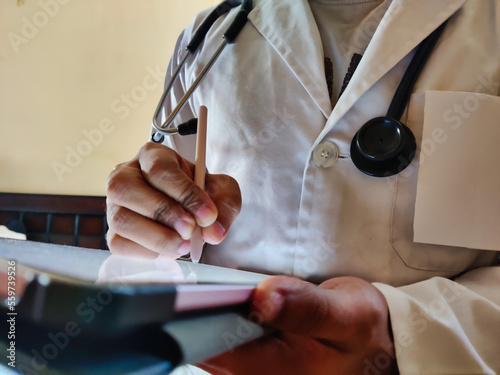 Konstfotografi Picture of a doctor wearing a white apron and stethoscope using a tablet
