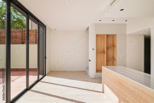 Foto Large bright spacious kitchen with wooden furniture and closed black metal sliding glass doors with access to the terrasse