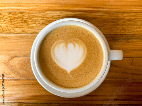 A cup of coffee latte on a wooden table. A mug of flat white coffee, latte, cappuccino on a wooden background. Coffee art. Heart flower shape latte art