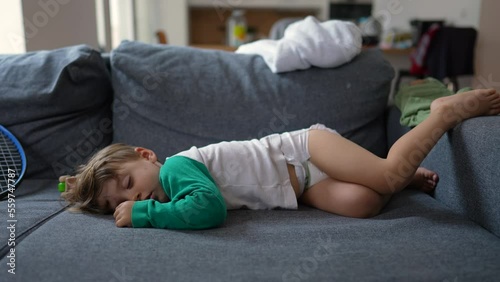 Funny little boy laying on sofa sleeping during afternoon nap. Baby toddler wearing diapers asleep on couch