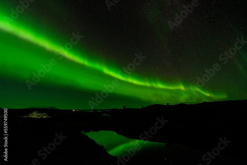 Aurora Borealis green beams with lake reflection