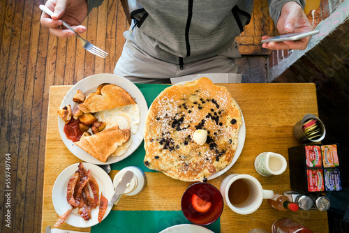 Man sitting in front of breakfast food, using smartphone