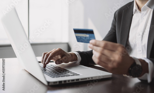 Wallpaper Mural Man holding credit card and using laptop computer at office. Businessman or entrepreneur working. Online payment, shopping, e-commerce, internet banking, spending money, business concept. Torontodigital.ca