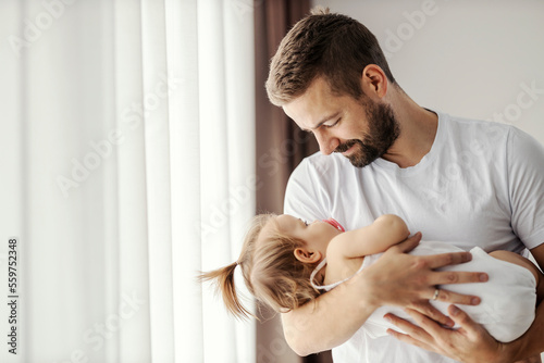 Photography A happy father is holding his daughter in arms and putting her to sleep