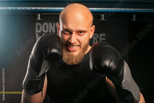 bald men in boxing gloves boxing rack angrily stares into the camera at the opponent © Anton