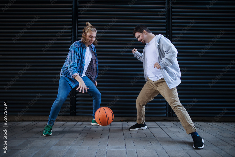 Man with down syndrome playing basketball outdoor with his friend