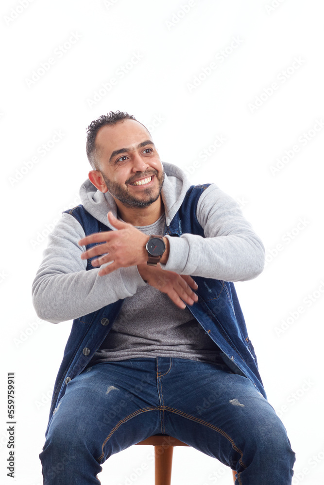 a portrait of an attractive young man in jeans shirt sitting on the chair isolated on white background, happy smiling man sitting on chair.happy emotions. a portrait of an attractive young man in jeans shirt sitting on the chair isolated on white background, happy smiling man sitting on chair.happy emotions.