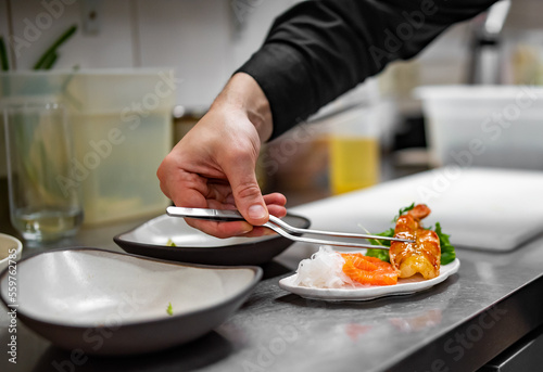 chef cooking slice salmon fish and shrimp with salad on kitchen