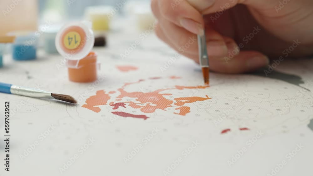 A brush in a jar with water, A girl paints Pictures by Numbers, close-up. A brush in a jar with water, A girl paints Pictures by Numbers, close-up.