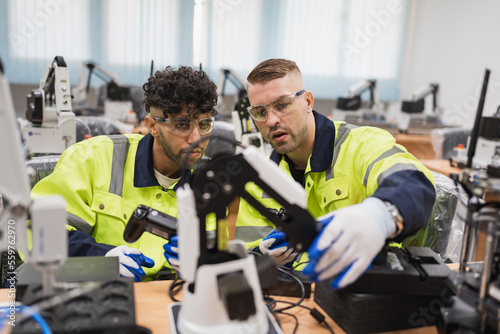Two caucasian engineer man learning control and repair arm robot in class 