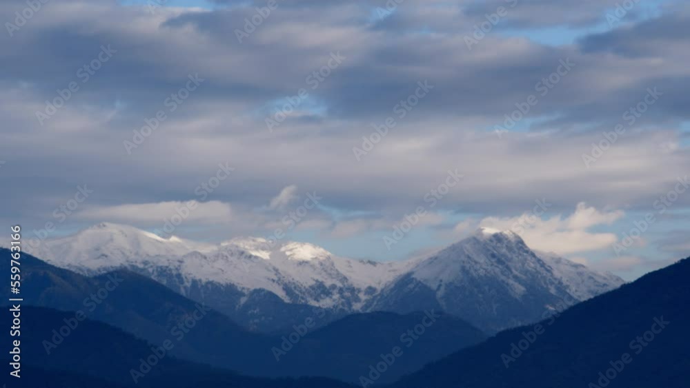 White clouds glide between the mountain peaks. Time laps of mountain peaks and clouds. Mountain delightful landscape White clouds glide between the mountain peaks. Time laps of mountain peaks and clouds. Mountain delightful landscape
