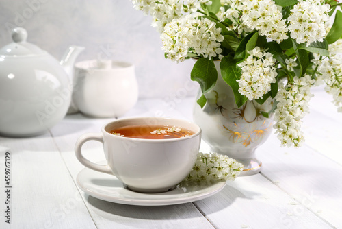 Useful spring tea with bird cherry in a white cup on a light background