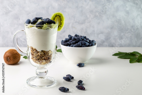 Muesli, yogurt, honeysuckle and kiwi in a transparent glass. Delicious and healthy breakfast