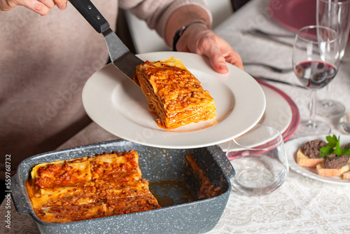 Photography A man serving homemade lasagne made with meat ragù sauce, bechamel and parmesan cheese