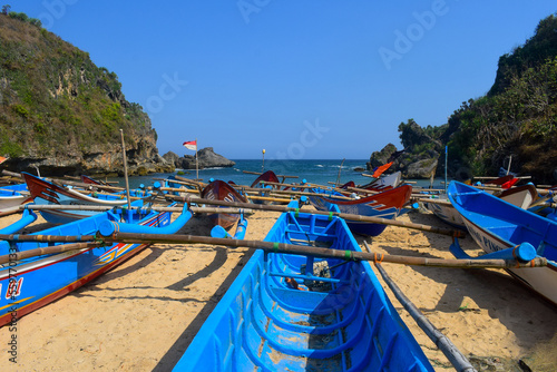 The view of white sand beach with blue sky view and fishing boat leaning on the beach © Rifki