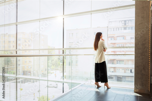 Full length of thinking businesswoman looking the city through window