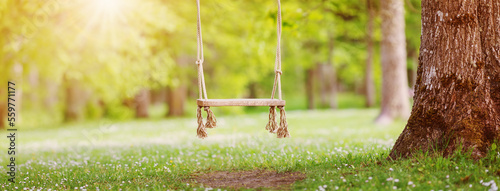 Empty swing hanging in the park in spring.