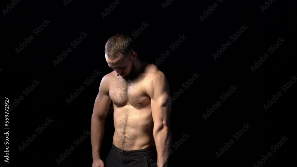 Muscular shirtless man playing with muscles, on black background. Locked down video Muscular shirtless man playing with muscles, on black background. Locked down video