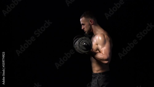Strong handsome shirtless sport man making weightlifting with dumbbells. Side view on black background, locked down real time video