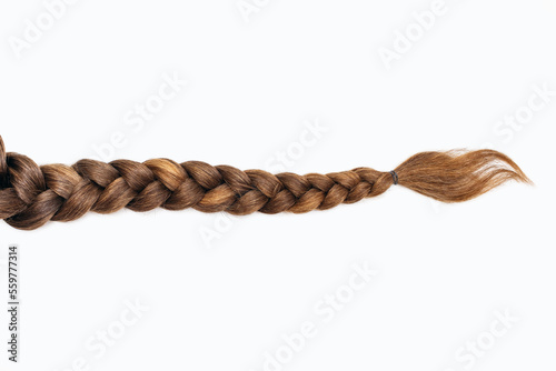 Female hair in the form of a braid on a white isolated background. Red hair braided close-up. Beautiful healthy natural female hair without dyeing photo