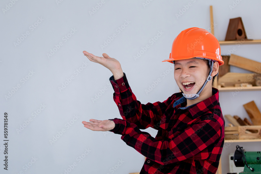 Lovely Asian carpenter boy acting present his work in front of DIY woodworking table carpentry shop with copy space Lovely Asian carpenter boy acting present his work in front of DIY woodworking table carpentry shop with copy space
