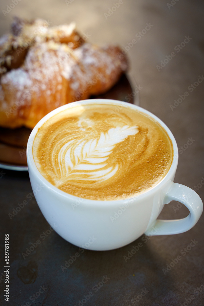 A cup of cappuccino coffee on a table in a cafe. Coffee hot drink in a ceramic cup for breakfast in the morning. A cup of cappuccino coffee on a table in a cafe. Coffee hot drink in a ceramic cup for breakfast in the morning.