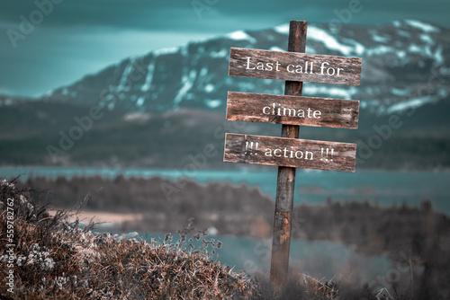 last call for climate action text quote engraved on wooden signpost outdoors in landscape looking polluted and apocalyptic. photo