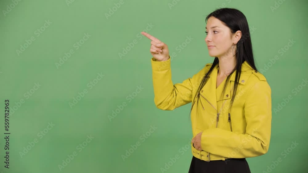 A young beautiful Caucasian woman points at bullet-point text - green screen studio A young beautiful Caucasian woman points at bullet-point text - green screen studio