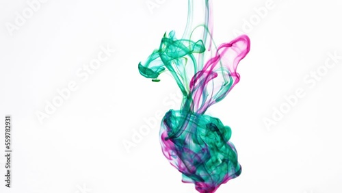 Hypnotic Liquid Ink. Slow-Motion Green and Purple Mixing in Water with White Background.