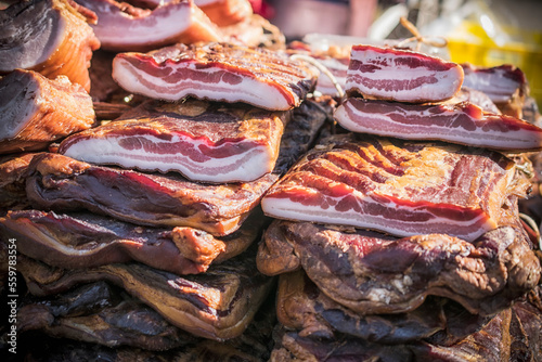 An outdoor stall with pieces of bacon and dried meat being sold photo