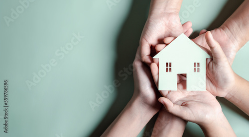 Hands holding wooden house, family home, homeless housing, mortgage crisis and home protecting insurance, international day of families, foster home care, family day care, stay home concept photo