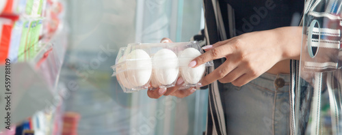 Caucasian woman buying eggs in supermarket.