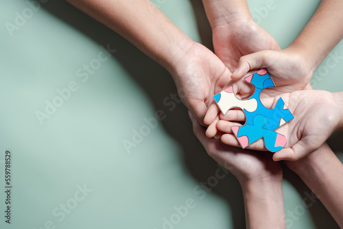 Color puzzle symbol of awareness for autism spectrum disorder family support. Father, Mother, Children holding jigsaw puzzle Autism World Awareness Day.