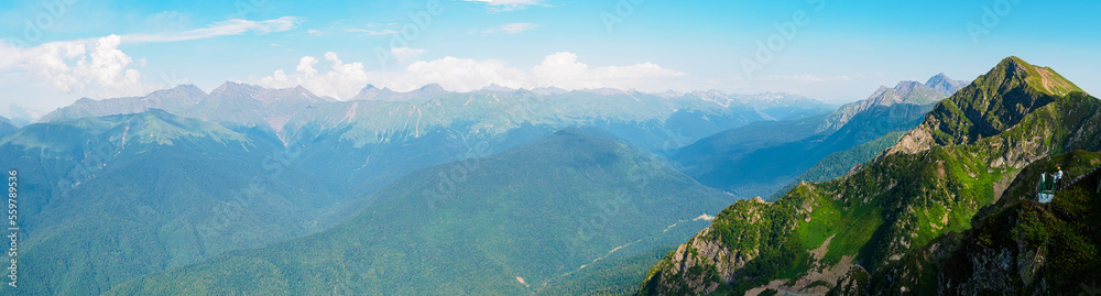 Panorama: View from the top of Roza Peak to the Caucasian mountains in summer on a sunny day