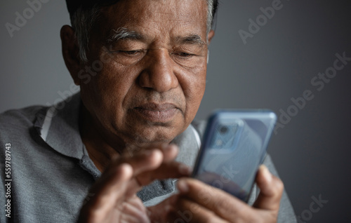 Portrait, sad old man, unhappy elderly man thinking while using smart phone at home