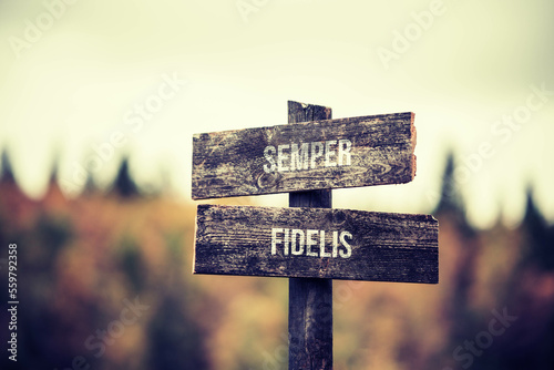 vintage and rustic wooden signpost with the weathered text quote semper fidelis, outdoors in nature. blurred out forest fall colors in the background. photo
