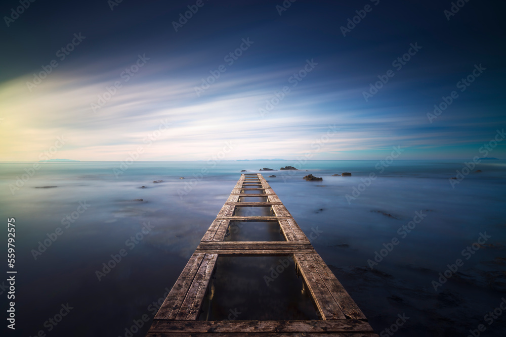 Fototapeta premium Wooden pier remains in a blue sea. Long Exposure.