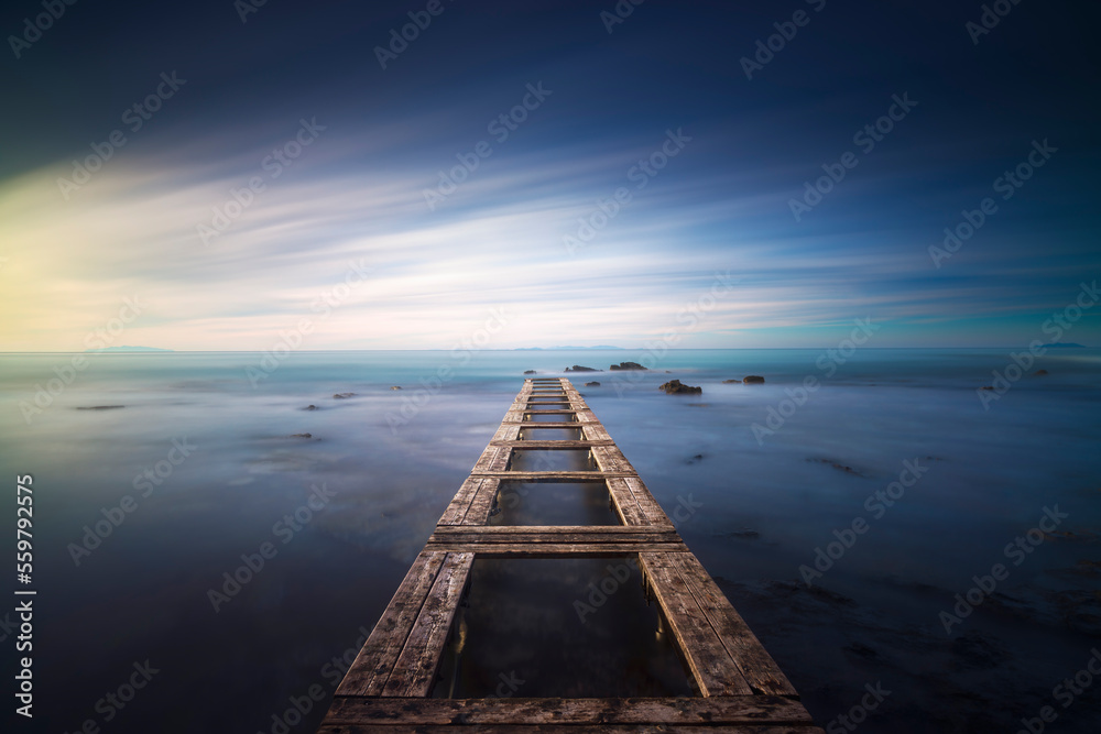 Wooden pier remains in a blue sea. Long Exposure.